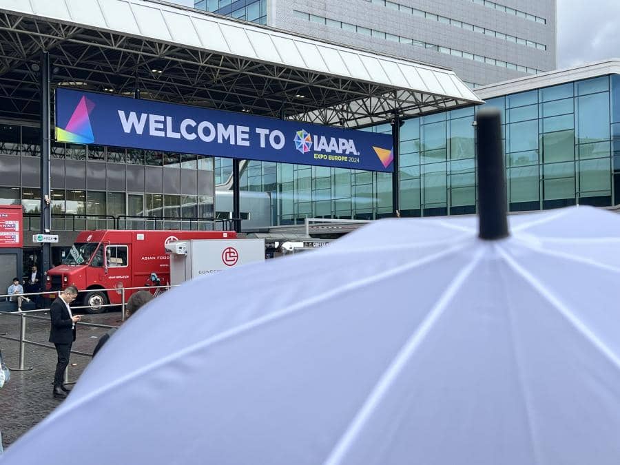 A white umbrella keeps the rain off a man's head at IAAPA Expo Europe 2024